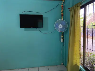 a room with a blue wall with a fan and a television at viajero solitario in Buenos Aires