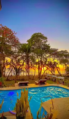 a large swimming pool with trees in the background at Hotel Beachfront Vista Hermosa in Jacó