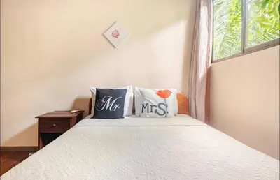 a bedroom with a bed with pillows and a window at Hotel Beachfront Vista Hermosa in Jacó