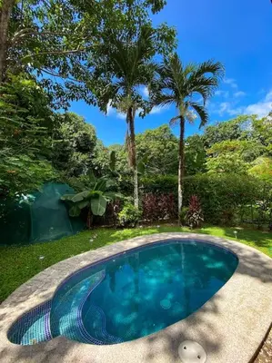 a swimming pool in a yard with palm trees at Beautiful 2BR Casita with Pool & Parking in Jacó