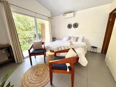a bedroom with a bed and a chair and a window at Casa Jalapa with private pool in Uvita