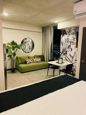a living room with a green couch and a table at Studio Sabana Secrt 3011 in San José