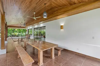 a dining room with a wooden table and benches at Spacious 3-Bedroom Coastal Home with Shared Pool, Outdoor Living & Steps to Playa Potrero in Potrero
