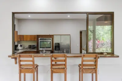 a kitchen with a counter with two chairs and a mirror at Spacious 3-Bedroom Coastal Home with Shared Pool, Outdoor Living & Steps to Playa Potrero in Potrero