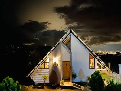 a small house with a lit up roof at night at Cabañas de Montaña Magia del Poás in Poás