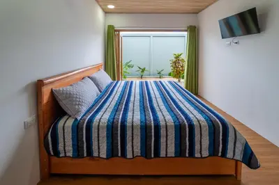 a bedroom with a bed with a striped comforter and a window at Casa Luna in Tanque
