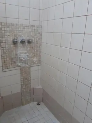 a bathroom with a shower with white tiles at Gaudy's Hostel in San José