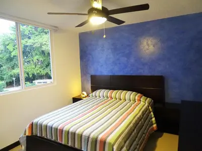 a bedroom with a bed with a blue wall at Jaco Costa Linda Condo in Jacó