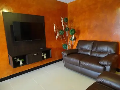 a living room with a leather couch and a flat screen tv at Jaco Costa Linda Condo in Jacó