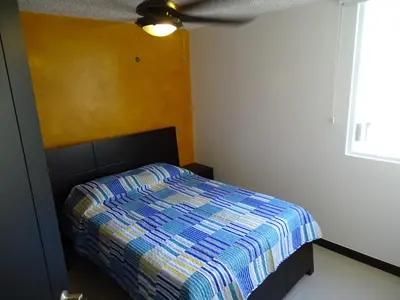 a bedroom with a bed with a striped comforter at Jaco Costa Linda Condo in Jacó