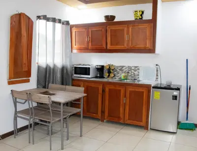 a kitchen with wooden cabinets and a table and a refrigerator at Lilo apartamento, bello y lujoso in Liberia