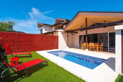 a backyard with a swimming pool and red chairs at Pop House with private pool at Ciudad del Mar in Jaco in Jacó