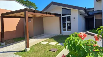 a wooden pergola in front of a house at Pop House with private pool at Ciudad del Mar in Jaco in Jacó