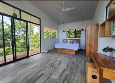 a bedroom with a bed and large windows at Jungle paradise in Ballena