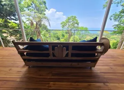 a swing on a porch with a view of the ocean at Jungle paradise in Ballena