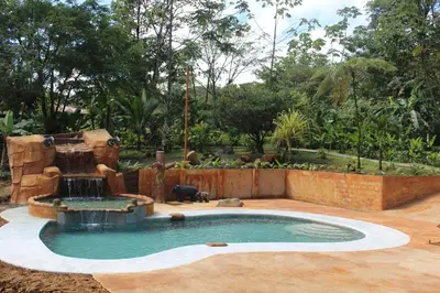 a pool with a water fountain in a yard at Hotel Catarata Río Celeste in Bijagua