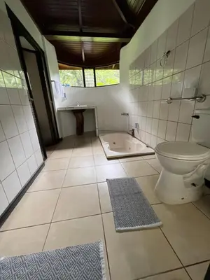a bathroom with a toilet and a bath tub at Hotel Catarata Río Celeste in Bijagua
