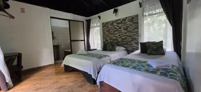 a bedroom with two beds and a brick wall at Hotel Catarata Río Celeste in Bijagua