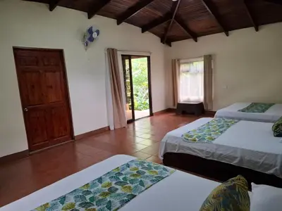 a room with two beds and a door to a patio at Hotel Catarata Río Celeste in Bijagua