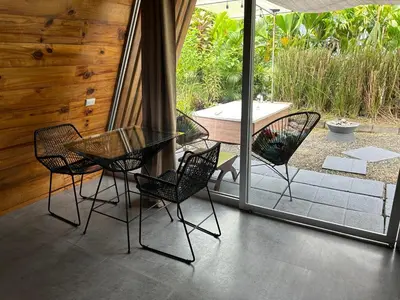 a glass table and chairs on a patio with a tub at IkI Tiny Villa in Fortuna