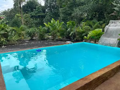 a blue swimming pool with a chair and trees at IkI Tiny Villa in Fortuna