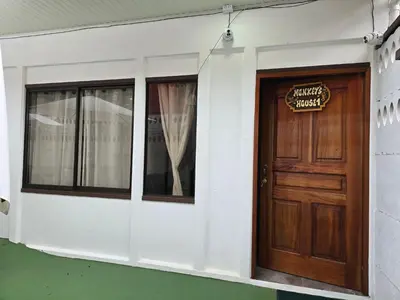 a building with a wooden door and a sign on it at Monkey House in Tortuguero