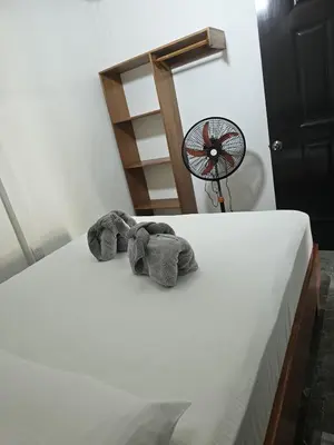 a stuffed elephant sitting on a bed next to a fan at Monkey House in Tortuguero