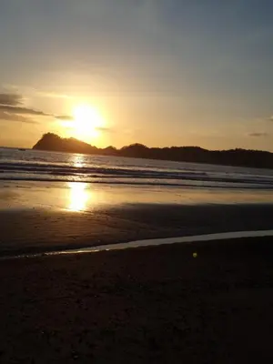 a sunset on a beach with the sun setting at Villas Gecko in San Juanillo