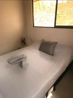 a bed with white sheets and a window at Villas Gecko in San Juanillo