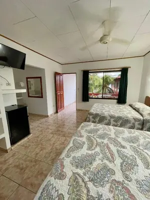a large bedroom with two beds and a fireplace at Apartotel Flamboyant in Jacó