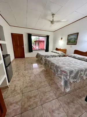 a hotel room with three beds and a television at Apartotel Flamboyant in Jacó
