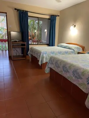a hotel room with two beds and a window at Apartotel Flamboyant in Jacó