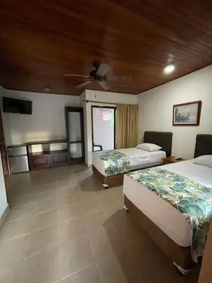 a hotel room with two beds and a ceiling at Apartotel Flamboyant in Jacó