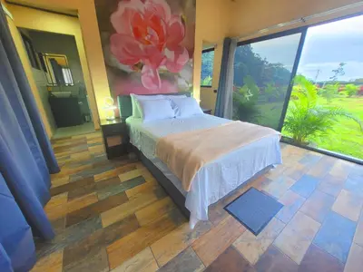 a bedroom with a bed and a large window at Casitas del Arenal in Fortuna