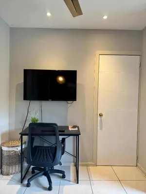 a desk with a chair and a television on a wall at Pipas Apartment in Tamarindo