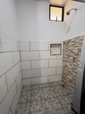a bathroom with a shower with white tiles and a window at Villa Granja Agua Azul-wi-fi-AC-6 Personas-parqueo in Agua Azul