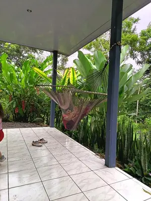 a woman standing on a porch with a hammock at Villa Granja Agua Azul-wi-fi-AC-6 Personas-parqueo in Agua Azul