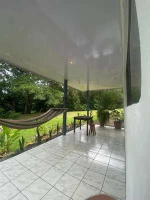 a porch with a hammock and a view of a field at Villa Granja Agua Azul-wi-fi-AC-6 Personas-parqueo in Agua Azul