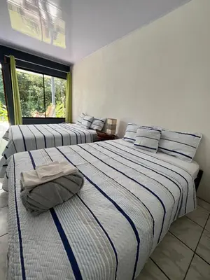 two beds in a room with a window at Villa Granja Agua Azul-wi-fi-AC-6 Personas-parqueo in Agua Azul