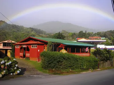 a rainbow in the sky above a red house at Hotel Bell Bird in Monteverde Costa Rica