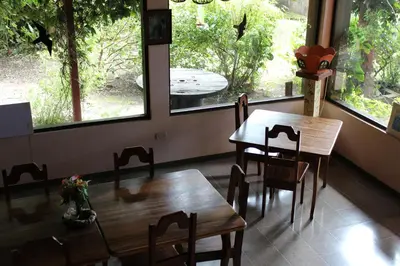 a dining room with two tables and chairs and windows at Hotel Bell Bird in Monteverde Costa Rica