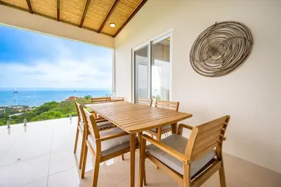 a dining room with a table and chairs and a large window at La Vista B8 in Tamarindo