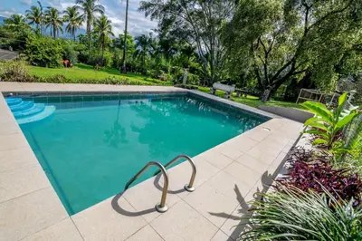 a swimming pool with blue water in a yard at Villa Margarita in Alajuela City