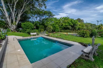 a swimming pool with a bench next to a yard at Villa Margarita in Alajuela City