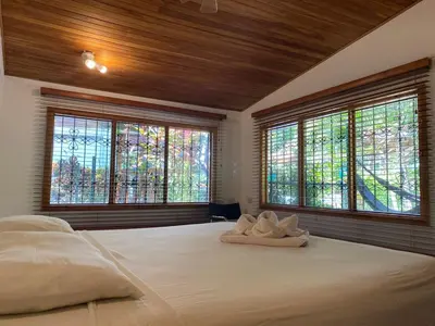 a bedroom with a large white bed with windows at Casa Aba Matapalo in Matapalo