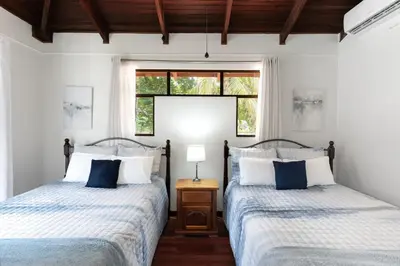 two beds in a room with two windows at Angels Sol Villa Hermosa 2b2b European Villa in Playa Hermosa