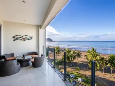 a room with a balcony with a view of the ocean at Beachfront Diamante del Sol 601S in Jacó