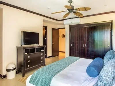 a bedroom with a bed with a ceiling fan and a tv at Beachfront Diamante del Sol 601S in Jacó