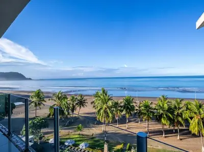 a view of a beach with palm trees and the ocean at Beachfront Diamante del Sol 601S in Jacó