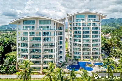 two tall buildings with palm trees and a resort at Beachfront Diamante del Sol 601S in Jacó